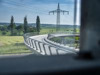 a bridge that is over some grass and some water and a highway and power lines