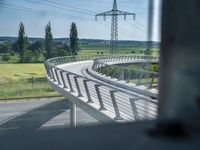 a bridge that is over some grass and some water and a highway and power lines