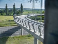 a bridge that is over some grass and some water and a highway and power lines