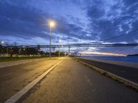 a bridge that is next to a river and a street with cars driving by it