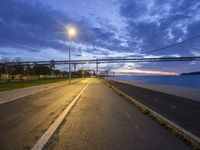 a bridge that is next to a river and a street with cars driving by it