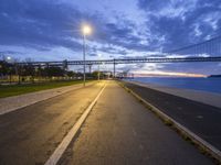 a bridge that is next to a river and a street with cars driving by it