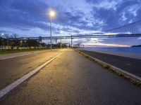 a bridge that is next to a river and a street with cars driving by it