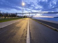 a bridge that is next to a river and a street with cars driving by it