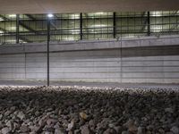 a black fire hydrant in a large, dimly lit parking garage space by a pile of rocks