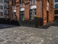 a sidewalk with chairs next to the brick building on the side, some have stairs and some buildings in the background