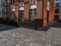 a sidewalk with chairs next to the brick building on the side, some have stairs and some buildings in the background