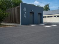 a metal building with a corrugated door in front of it and trees lining the street behind it