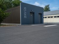 a metal building with a corrugated door in front of it and trees lining the street behind it