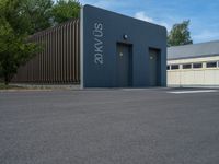 a metal building with a corrugated door in front of it and trees lining the street behind it