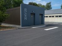 a metal building with a corrugated door in front of it and trees lining the street behind it