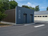 a metal building with a corrugated door in front of it and trees lining the street behind it