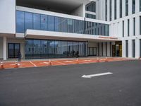 a building with large windows in the parking lot area outside it with orange arrows on the ground