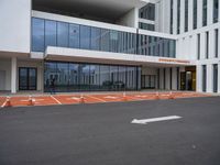 a building with large windows in the parking lot area outside it with orange arrows on the ground