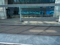 the outside of an office building with windows that reflect blue in the sunshine and street