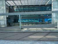 the outside of an office building with windows that reflect blue in the sunshine and street