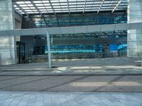 the outside of an office building with windows that reflect blue in the sunshine and street