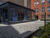 several plants sit in decorative concrete planters along the sidewalk of a building that is very modern