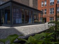 several plants sit in decorative concrete planters along the sidewalk of a building that is very modern