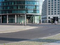 a city street intersection with tall glass buildings and a paved parking lot for the cyclist and pedestrians