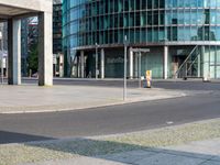 a city street intersection with tall glass buildings and a paved parking lot for the cyclist and pedestrians