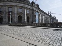 the building has a red flag flying high over it next to cobblestones and a metal railing