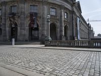 the building has a red flag flying high over it next to cobblestones and a metal railing