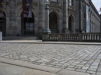 the building has a red flag flying high over it next to cobblestones and a metal railing