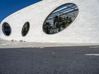 a street in front of a white building with two circular windows on the wall, as if in the street,