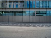 an empty parking lot is empty and a city building has many windows that are partially closed