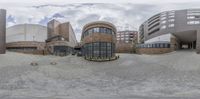 a fisheye photo of the building in the background and surrounding architecture behind it are two circular buildings, one is a library and the other is a museum