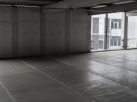 a picture of a building with an empty parking garage floor underneath and a window open