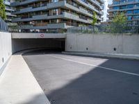 an empty parking area with a closed gated sidewalk underneath it next to some apartment complexes