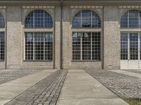 a picture of the front doors of a building with cobblestone paths in between them