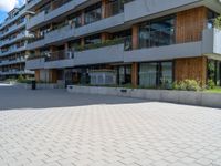 a person is riding down a brick road in front of apartment buildings on a cloudy day