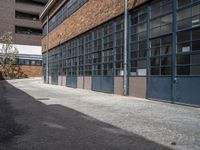 an old brick building with many windows and small door panels on it, in front of an empty courtyard