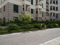 a walkway and some bushes in front of a building by the street next to it