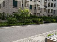 a walkway and some bushes in front of a building by the street next to it