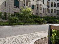 a walkway and some bushes in front of a building by the street next to it