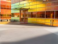 a colorfully painted building with an open doorway, a bench, and tables outside it