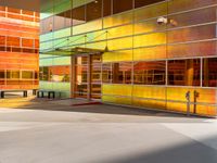 a colorfully painted building with an open doorway, a bench, and tables outside it