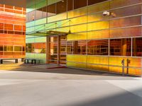 a colorfully painted building with an open doorway, a bench, and tables outside it