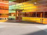 a colorfully painted building with an open doorway, a bench, and tables outside it