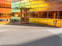 a colorfully painted building with an open doorway, a bench, and tables outside it