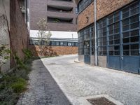 an empty brick building next to a small street with a door and a manhole