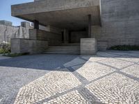 there is a very large courtyard with some stairs in front of a building with stone floors