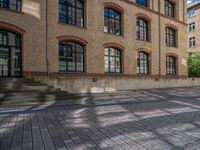 a brick courtyard has steps leading up to it, and a blue umbrella is on the ground