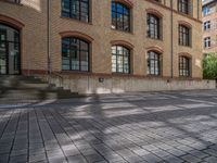 a brick courtyard has steps leading up to it, and a blue umbrella is on the ground