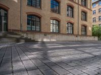 a brick courtyard has steps leading up to it, and a blue umbrella is on the ground