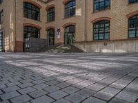 a brick courtyard has steps leading up to it, and a blue umbrella is on the ground